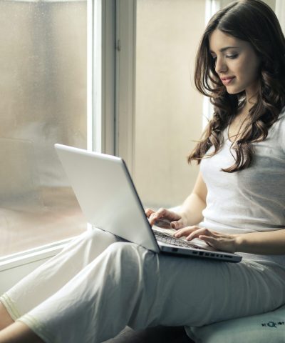 Arbetande kvinna med lockigt hår framför laptop